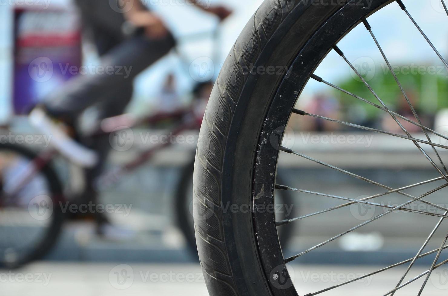 A BMX bike wheel against the backdrop of a blurred street with cycling riders. Extreme Sports Concept photo