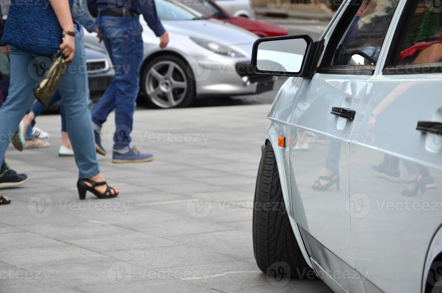 Diagonal view of a white glossy car that stands on a square of gray tiles photo