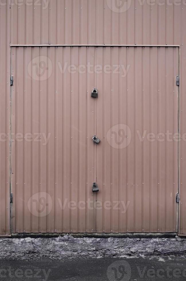 Texture of a metal brown wall with a gate closed for three locks photo