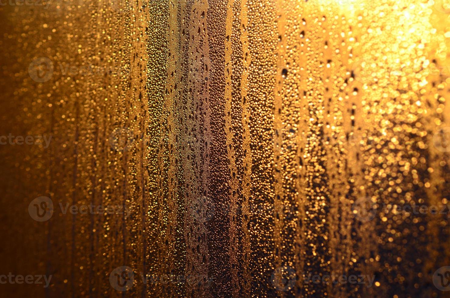 The texture of misted glass with a lot of drops and drips of condensation against the sunlight at dawn. Background image photo