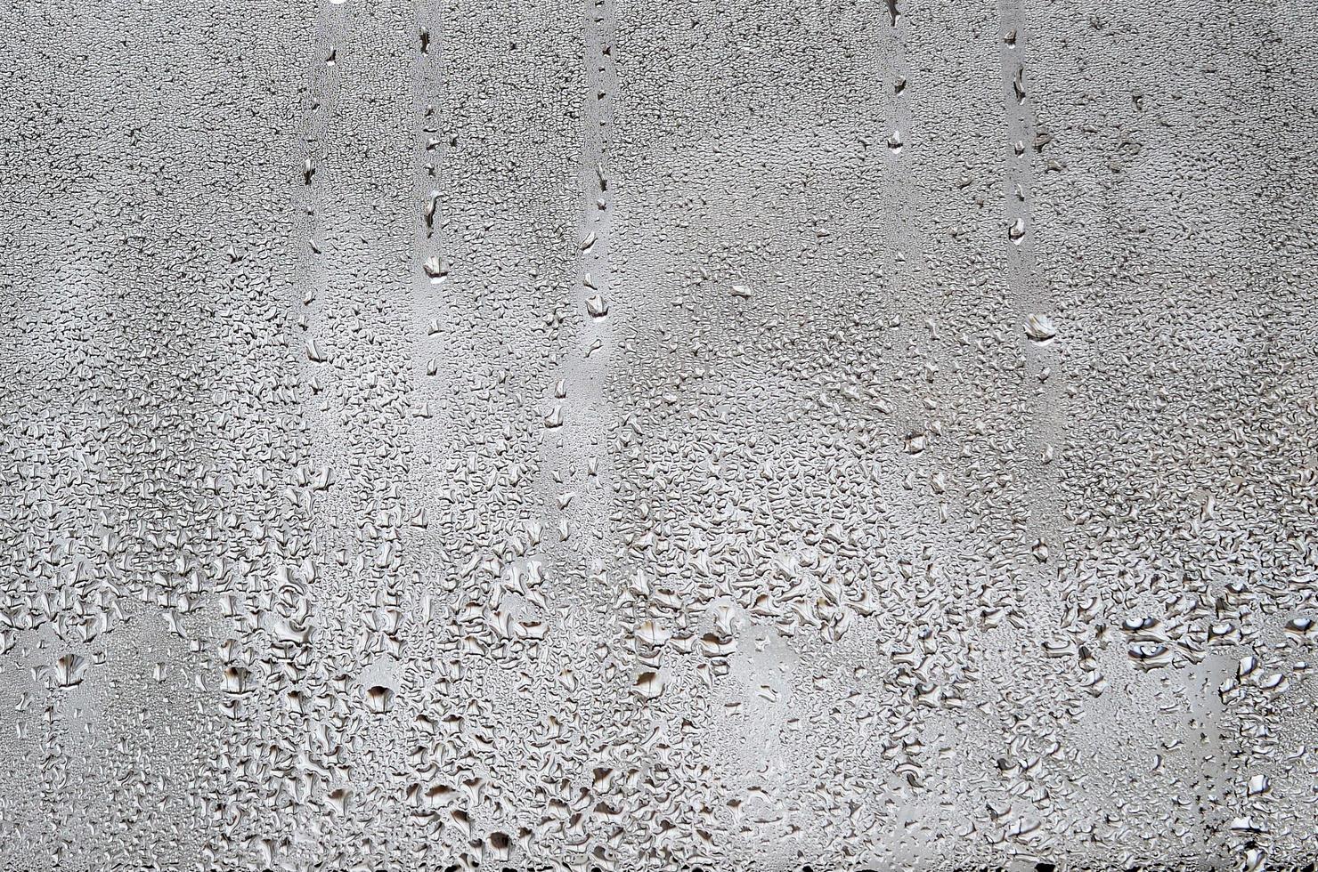 Texture of a drop of rain on a glass wet transparent background. Toned in grey color photo