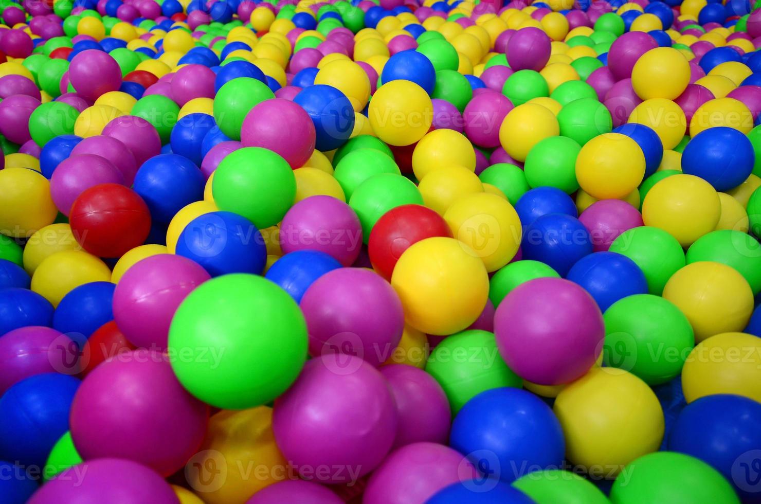 Many colorful plastic balls in a kids' ballpit at a playground. Close up pattern photo