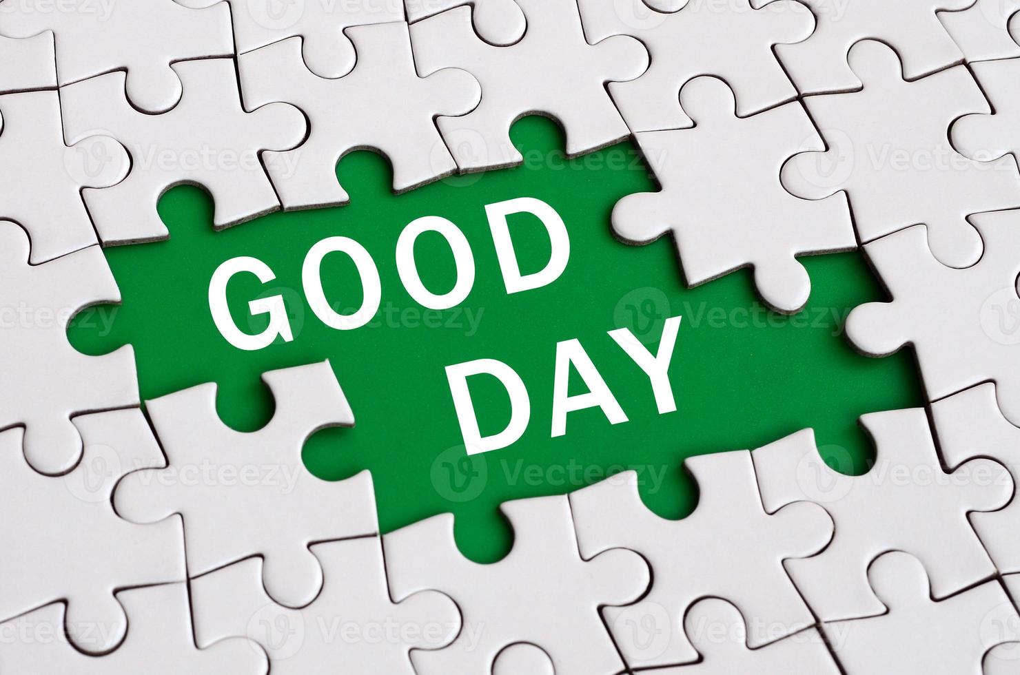 White jigsaw puzzle in assembled state with missing elements forming a green space with white inscription. Good day photo