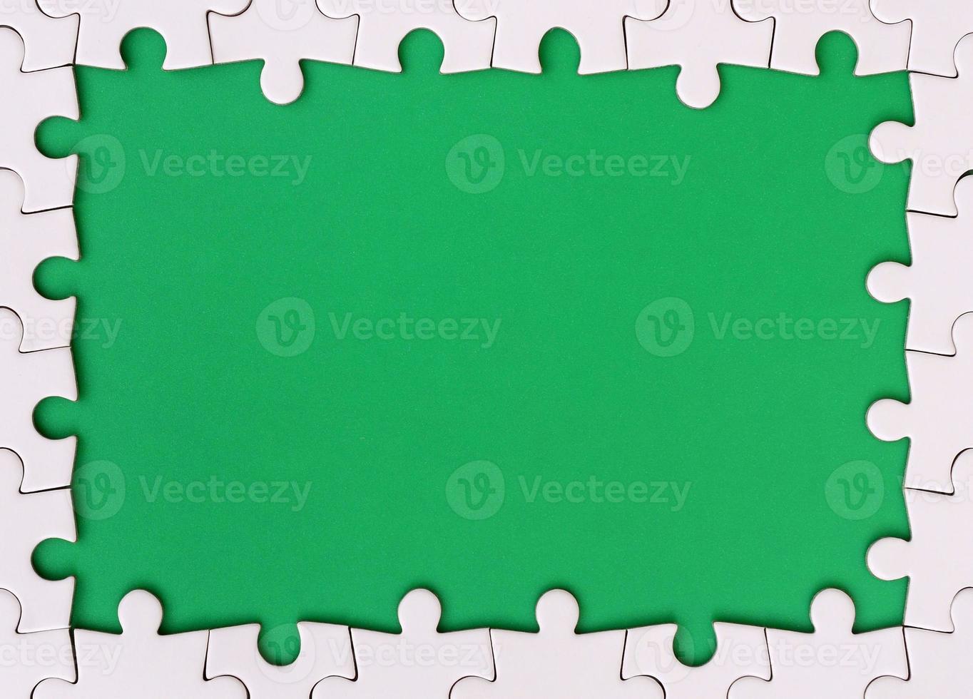 Framing in the form of a rectangle, made of a white jigsaw puzzle around the green space photo