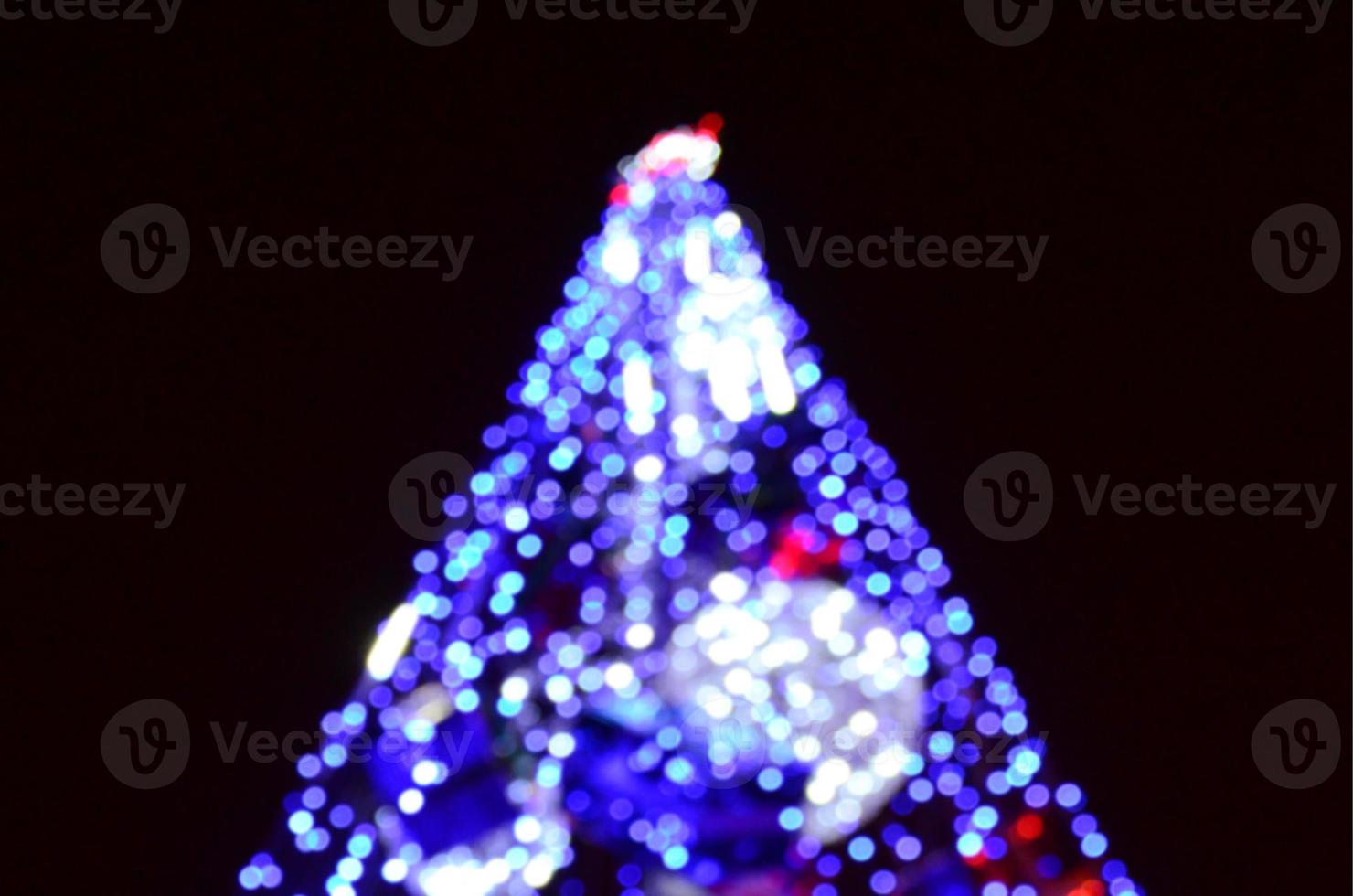 Blurred fragment of the New Year tree. Lots of round lights in blue photo
