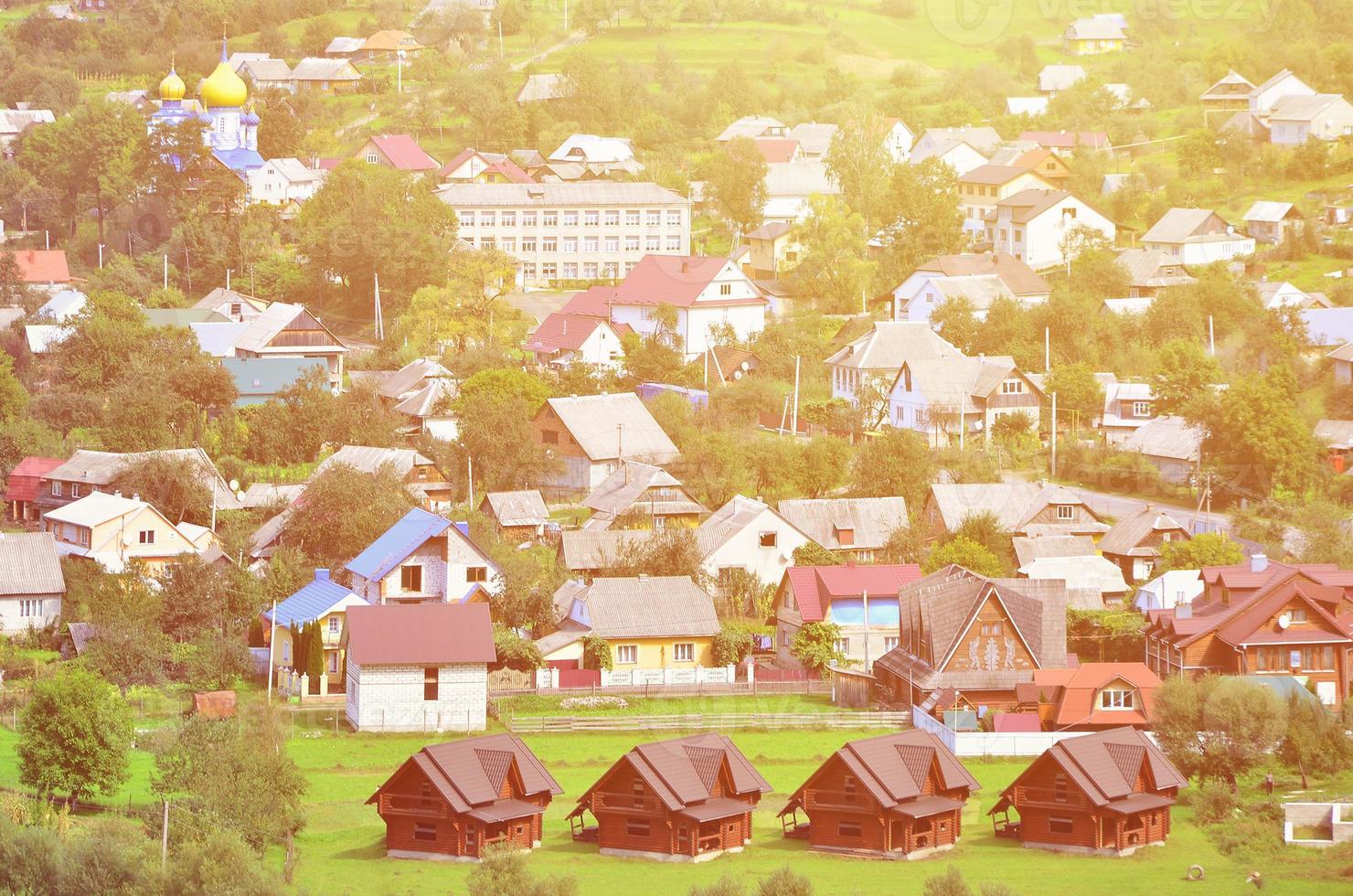 A beautiful view of the village of Mezhgorye, Carpathian region. A lot of residential buildings surrounded by high forest mountains and long river photo