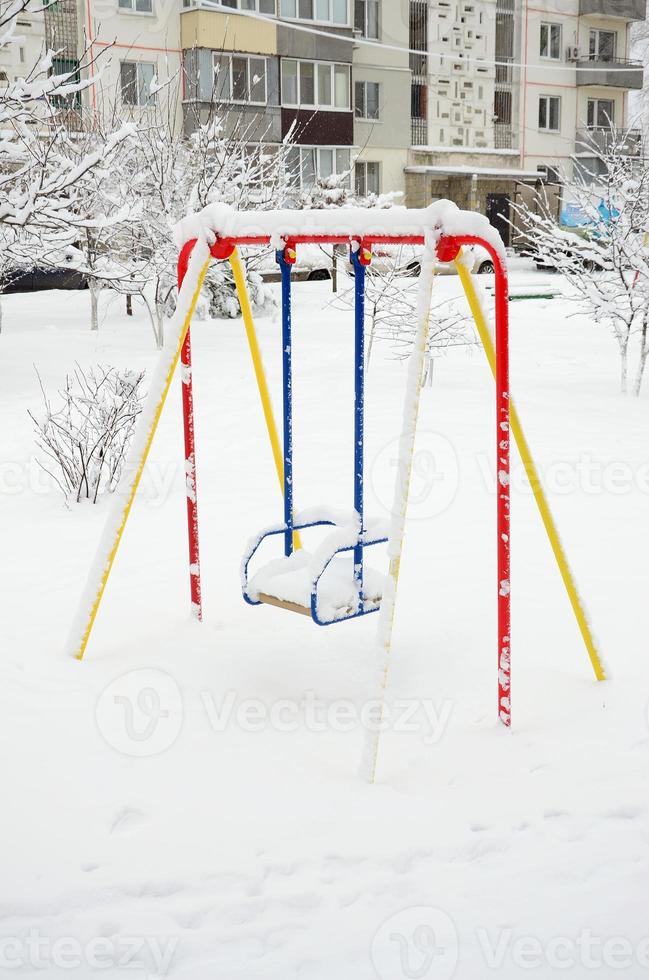 Children's swing, covered with a thick layer of snow after a heavy snowfall photo