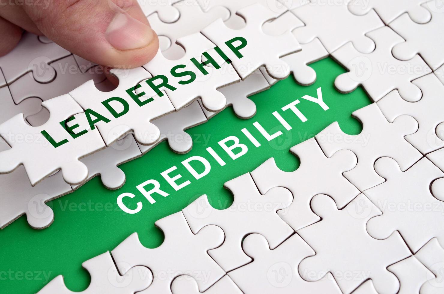 The human hand fills the last missing elements of the surface from the jigsaw puzzle. Image with words leadership and credibility photo