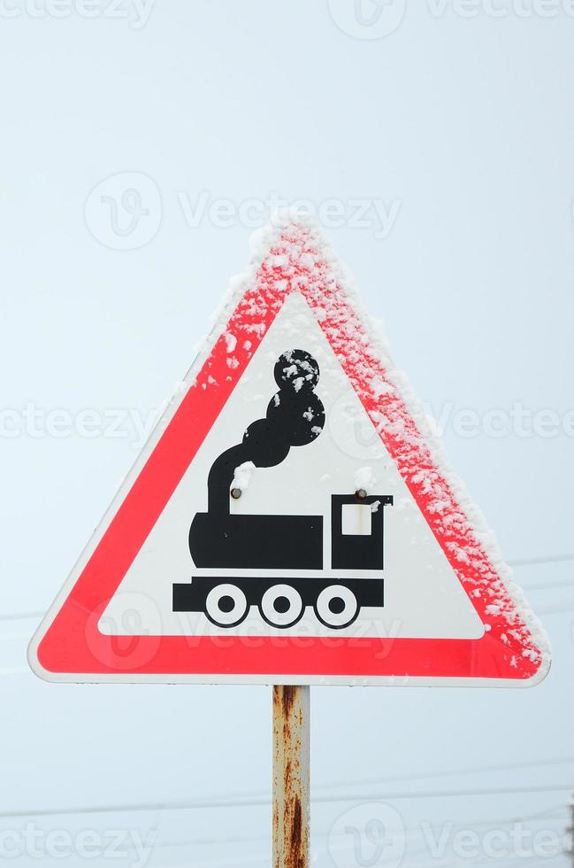 Railway crossing without barrier. A road sign depicting an old black locomotive, located in a red triangle photo