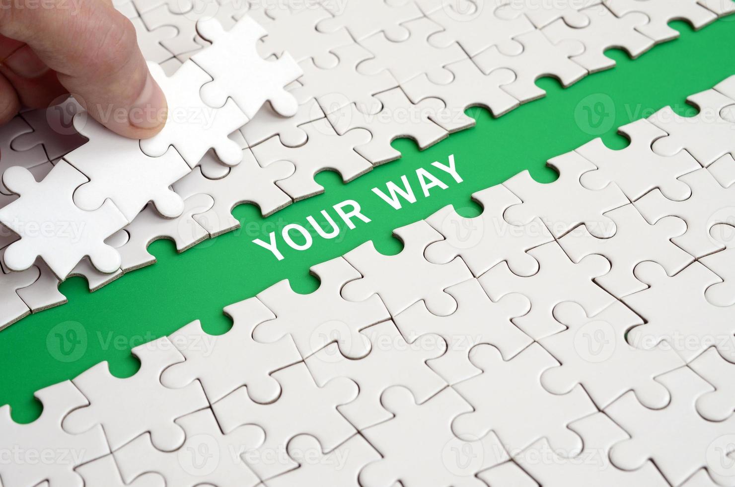 The human hand paves the way to the surface of the jigsaw puzzle, forming a green space with inscription. Your way photo