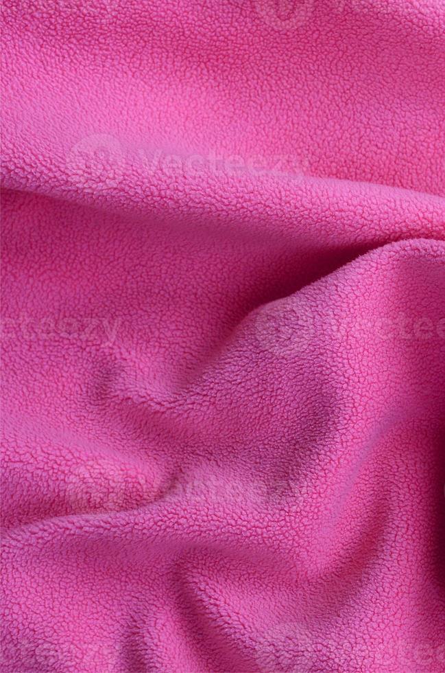 The blanket of furry pink fleece fabric. A background of light pink soft plush fleece material with a lot of relief folds photo