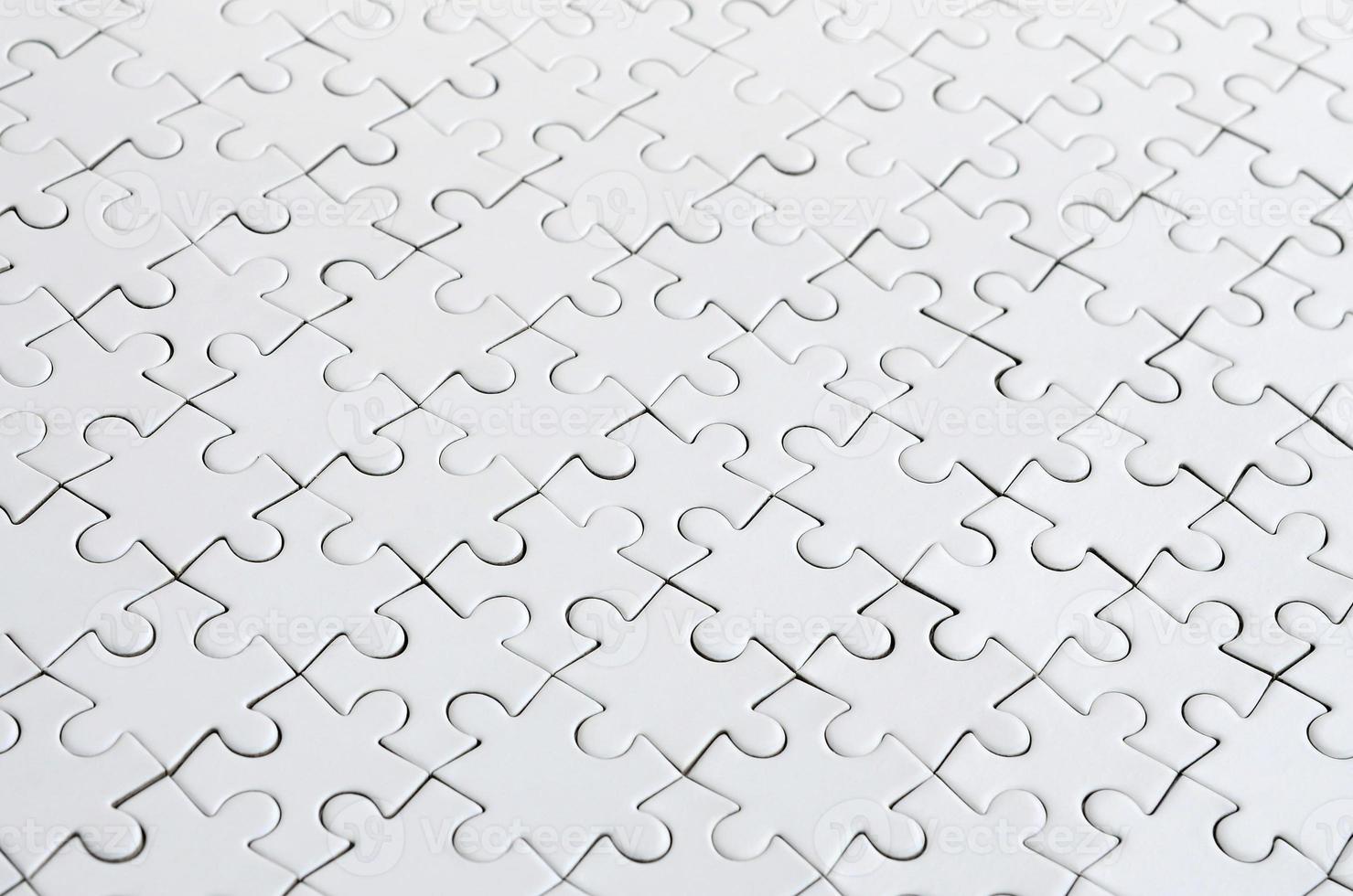 Close up of a white jigsaw puzzle in assembled state in perspective. Many components of a large whole mosaic are united photo