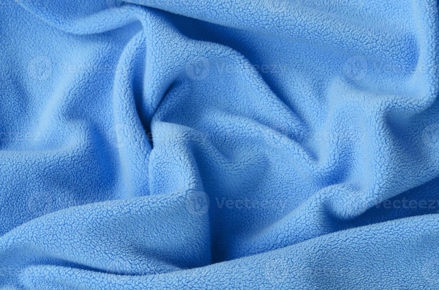 The blanket of furry blue fleece fabric. A background of light blue soft plush fleece material with a lot of relief folds photo