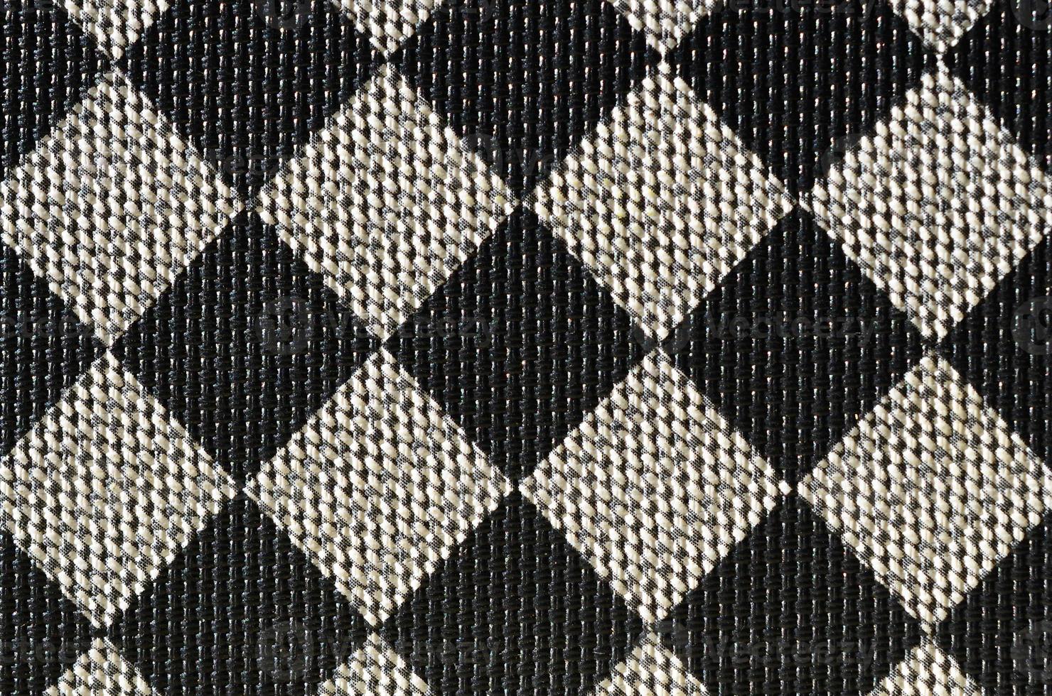 Plastic texture in the form of a very small cloth binding, painted in black and gray in the style of a chessboard. Macro shot photo