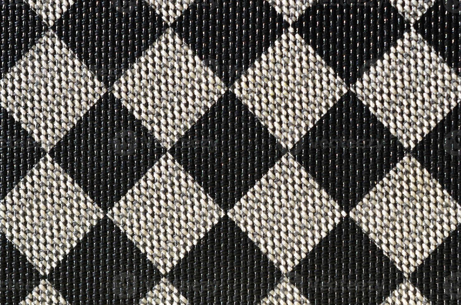 Plastic texture in the form of a very small cloth binding, painted in black and gray in the style of a chessboard. Macro shot photo