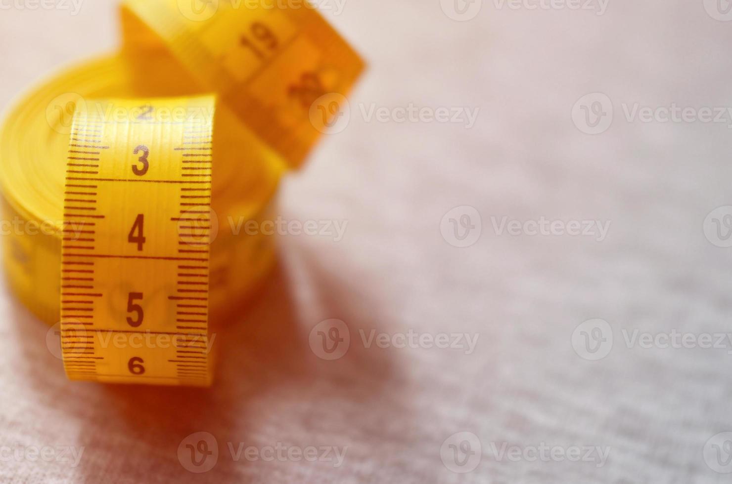 Yellow measuring tape lies on a gray knitted fabric photo