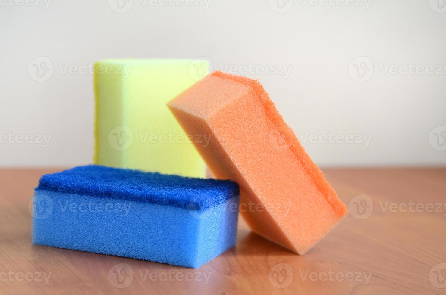 A few kitchen sponges lie on a wooden kitchen countertop. Colorful objects for washing dishes and cleaning in the house are ready for use photo