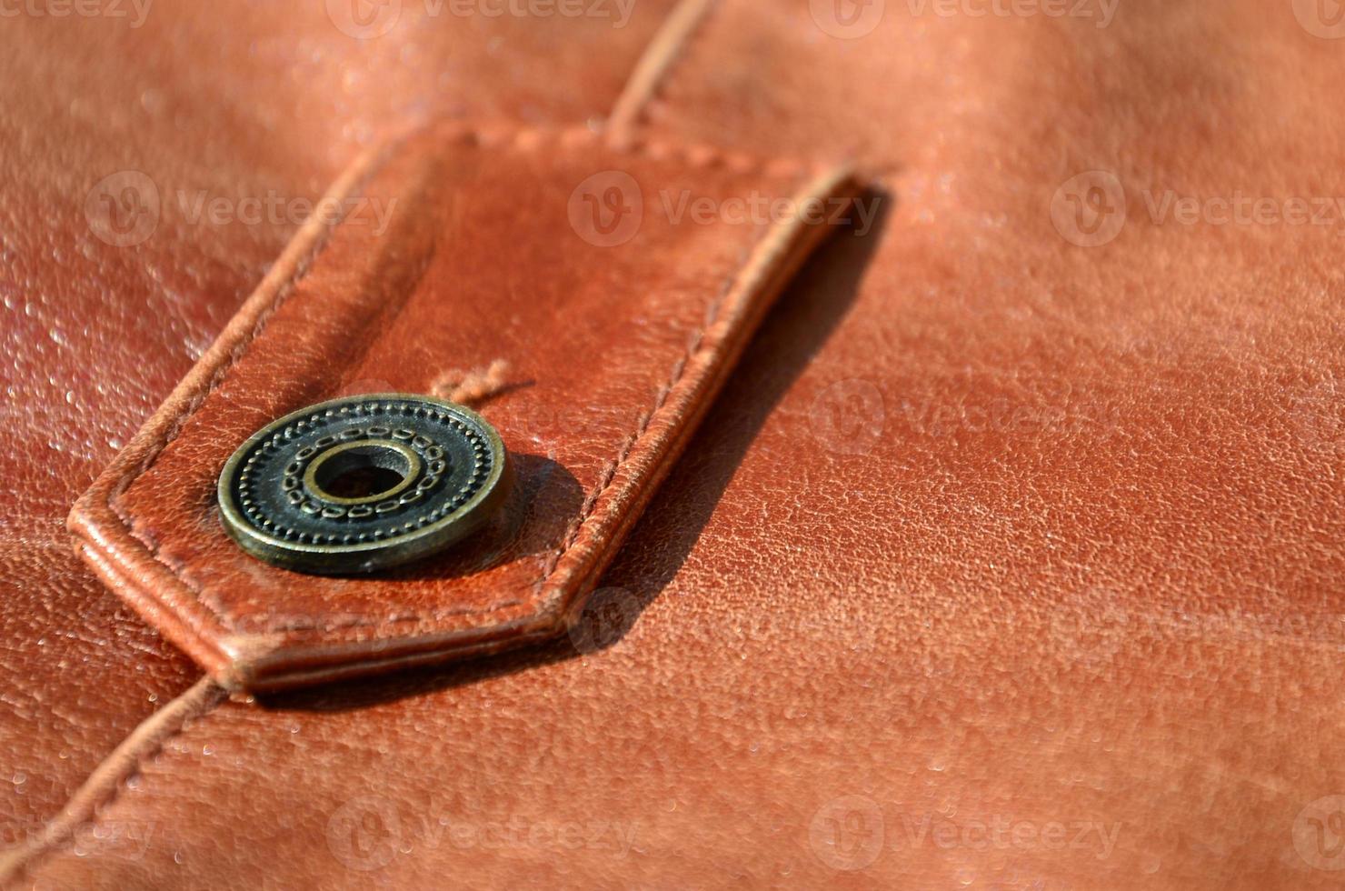 Brown leather texture. Useful as background for any design work. Macro photo of a button on outer clothing made of genuine leather