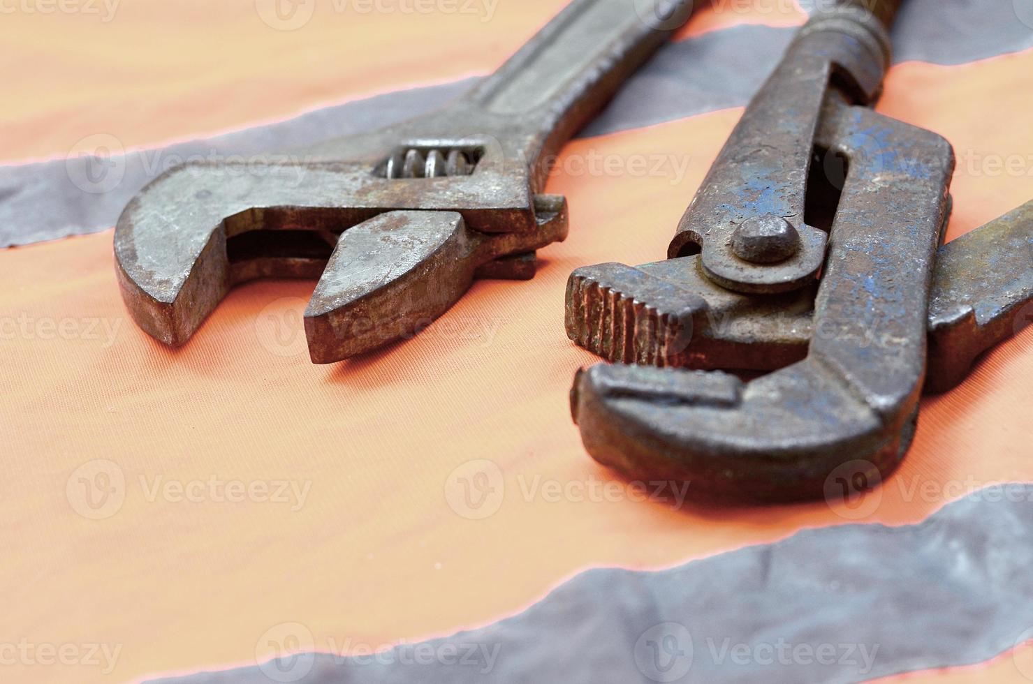 Adjustable and pipe wrenches against the background of an orange signal worker shirt photo