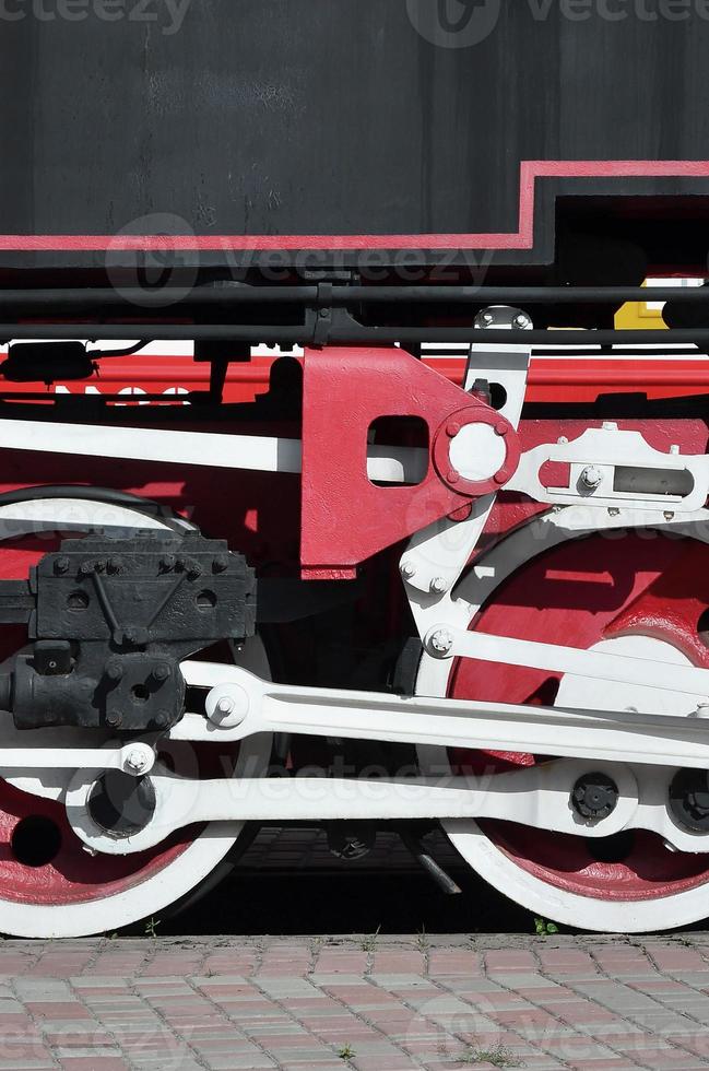 Wheels of the old black steam locomotive of Soviet times. The side of the locomotive with elements of the rotating technology of old trains photo