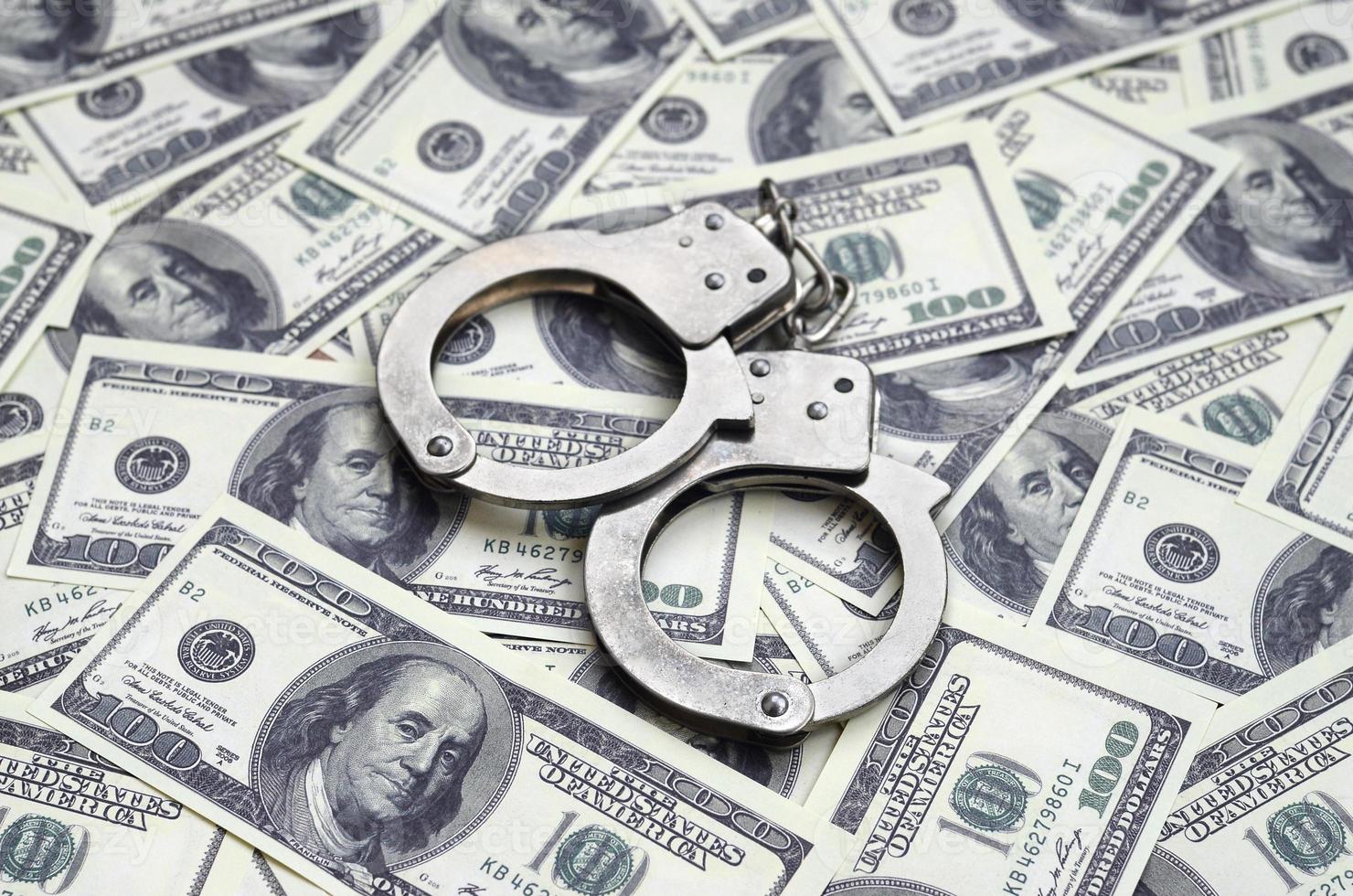 Police handcuffs lie on a lot of dollar bills. The concept of illegal possession of money, illegal transactions with US dollars. Economic Crime photo