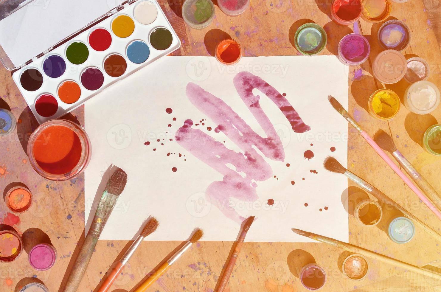Still life with painted sheet of paper and jars of watercolor and gouache paint photo
