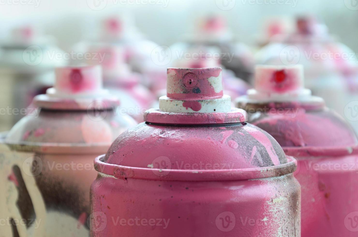 A lot of dirty and used aerosol cans of bright pink paint. Macro photograph with shallow depth of field. Selective focus on the spray nozzle photo
