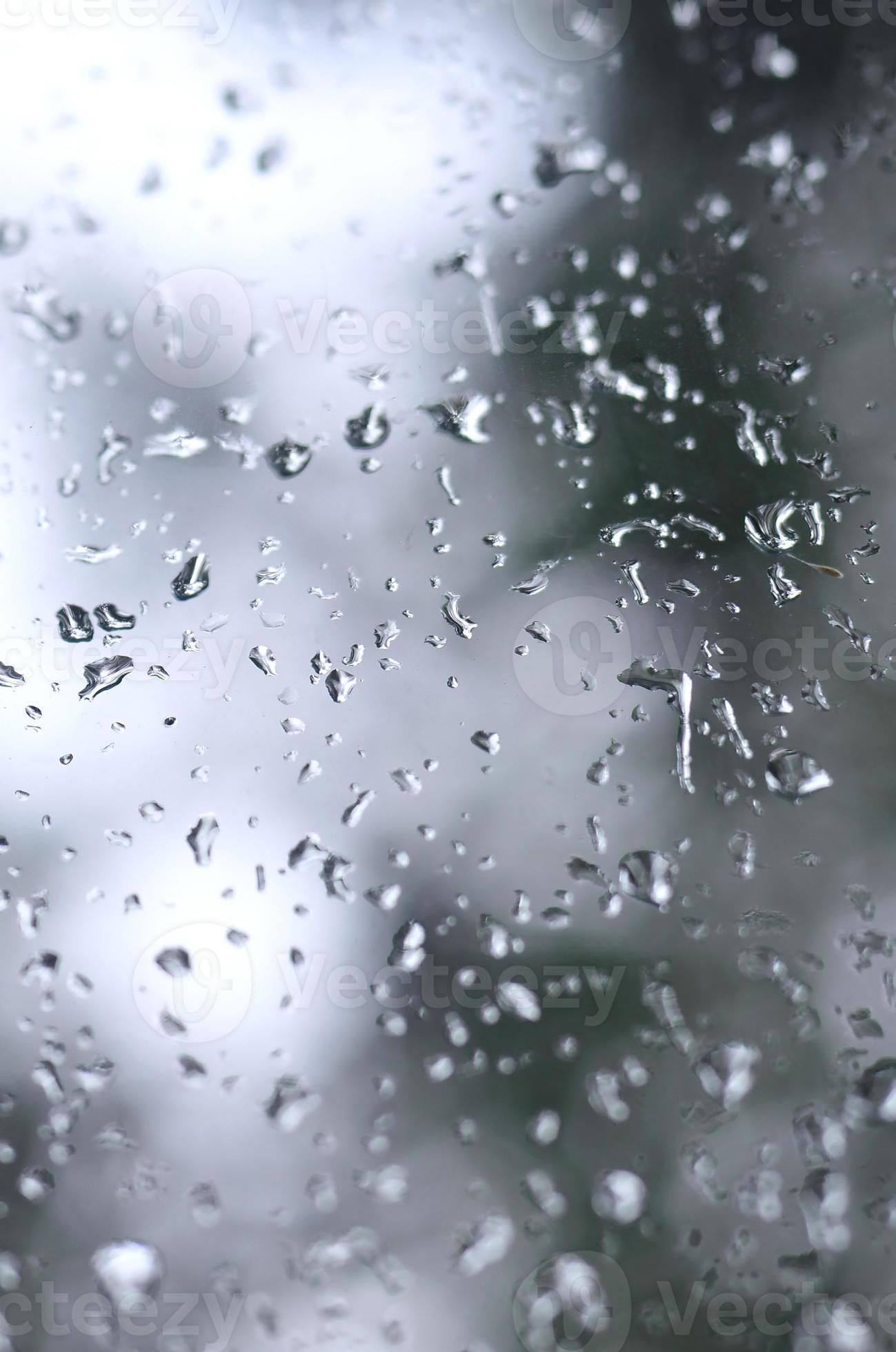 A photo of rain drops on the window glass with a blurred view of the  blossoming green trees. Abstract image showing cloudy and rainy weather  conditions 12583829 Stock Photo at Vecteezy