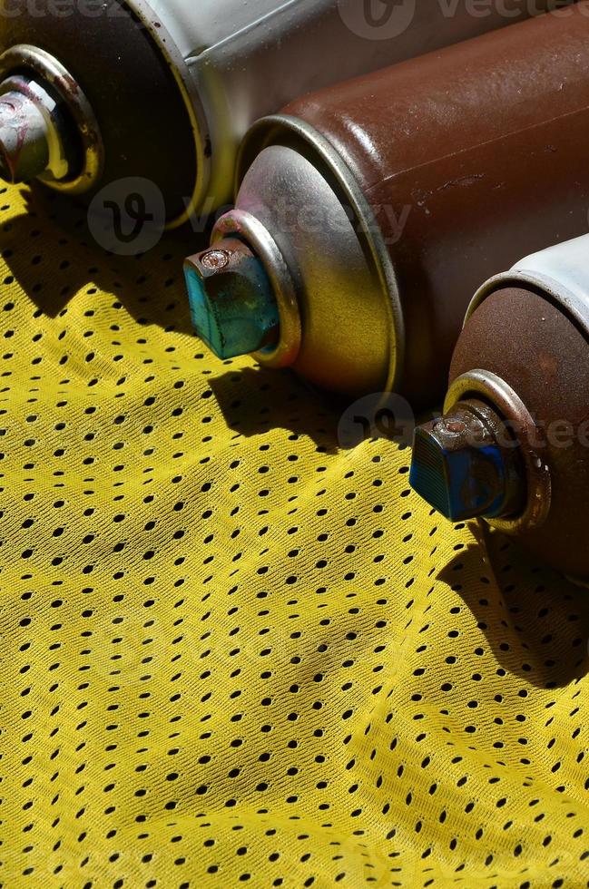 Several used aerosol paint sprayers lie on the sports shirt of a basketball player made of polyester fabric. The concept of youth street art, active sports and eventful lifestyle photo