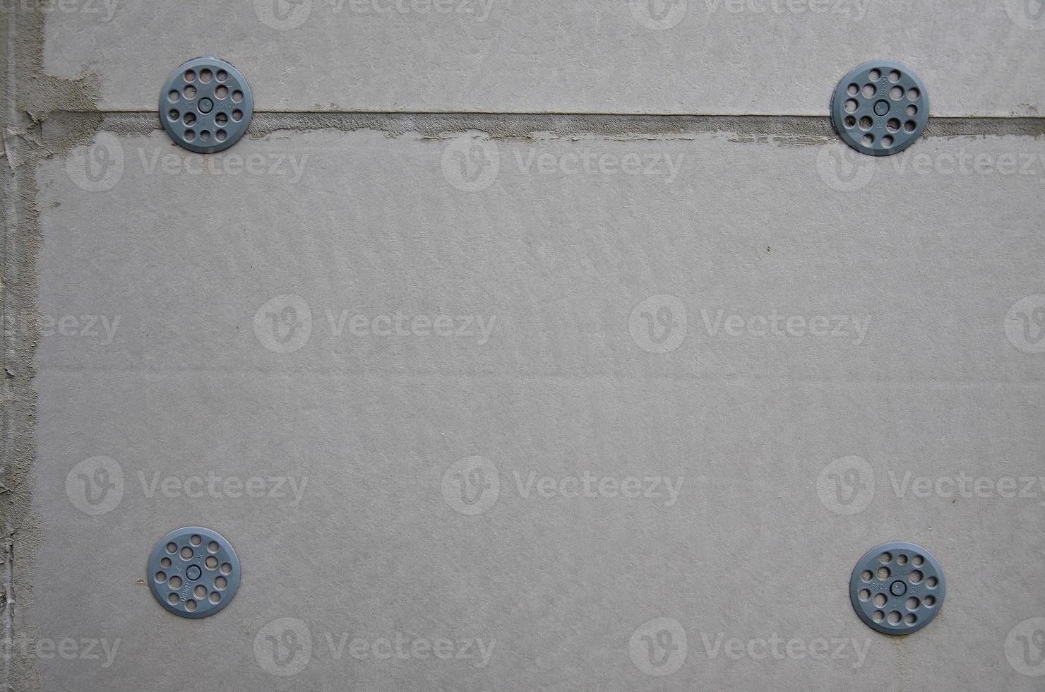 la textura de la pared, recubierta con placas de poliestireno expandido gris, que se refuerzan con tacos de plástico tipo paraguas. etapa de aislamiento de la pared foto