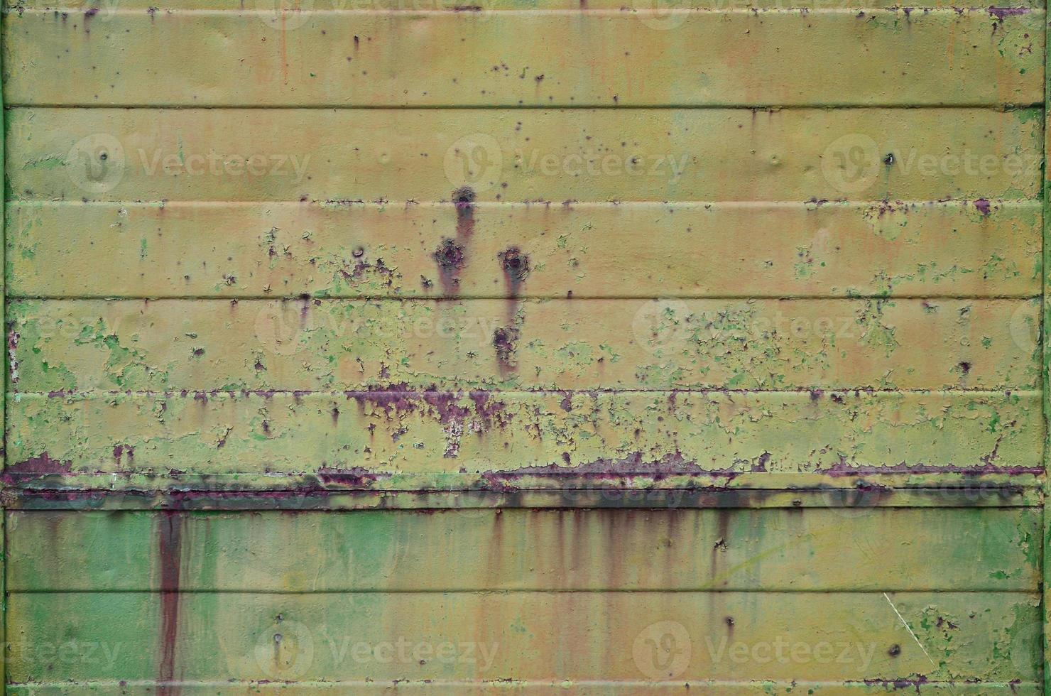 Texture of an old yellow metal wall with significant damage from exposure to unfavorable weather conditions and dampness photo