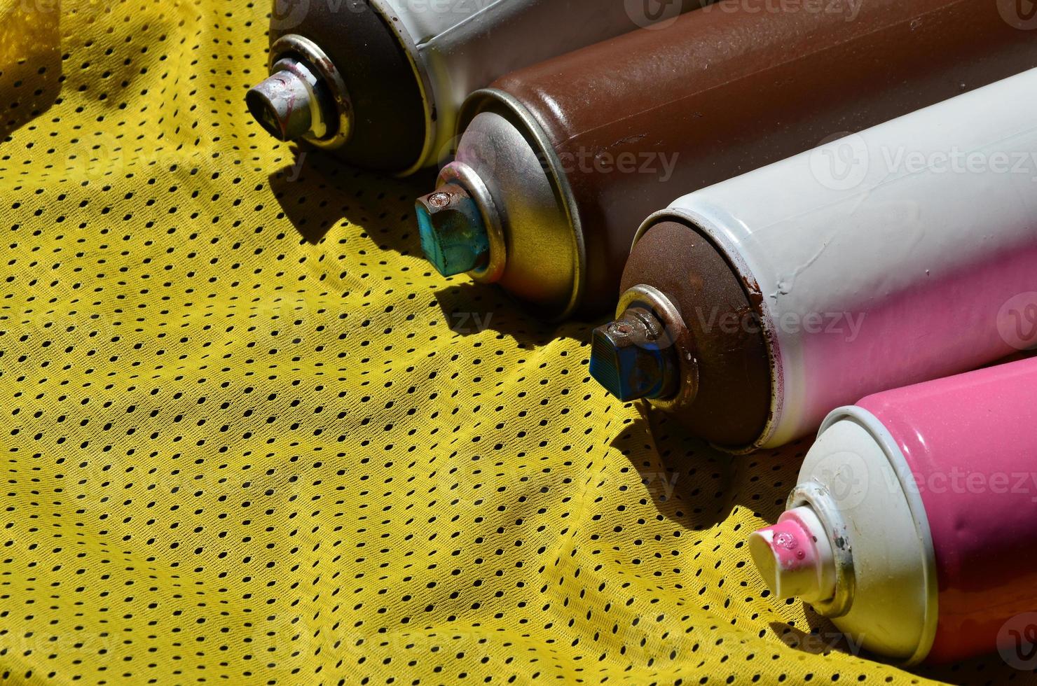 Several used aerosol paint sprayers lie on the sports shirt of a basketball player made of polyester fabric. The concept of youth street art, active sports and eventful lifestyle photo