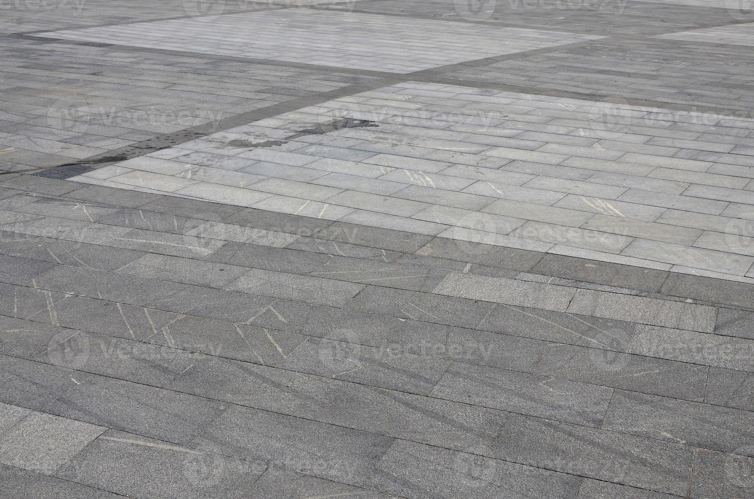 The texture of granite paving tiles from a variety of square shaped platforms under bright sunlight photo