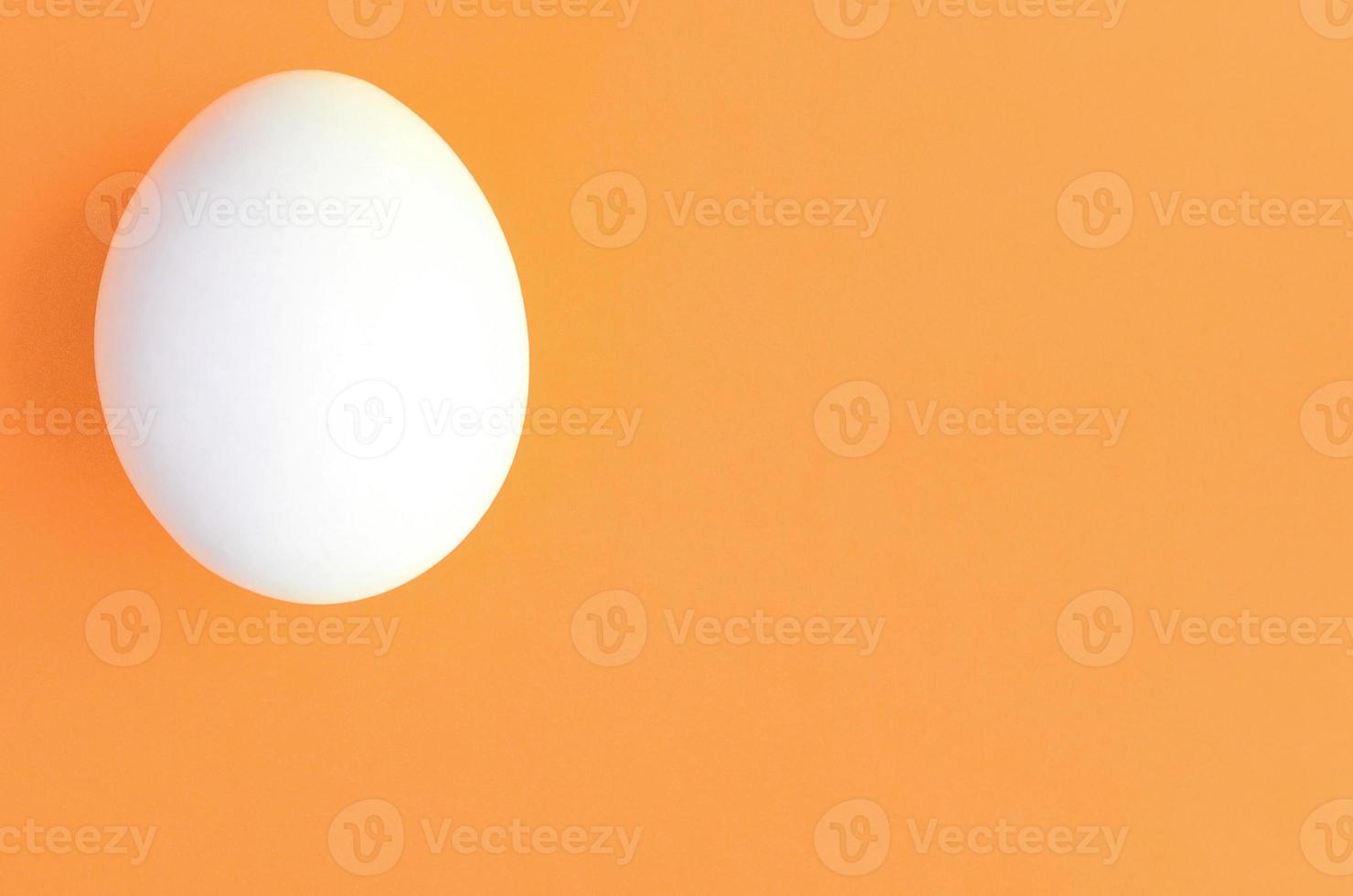 un huevo de pascua blanco sobre un fondo naranja brillante foto