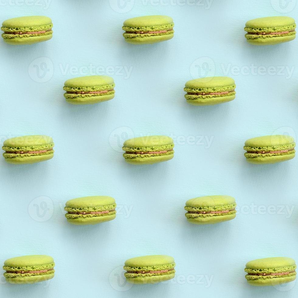 Green dessert cake macaron or macaroon on trendy pastel blue background top view. Flat lay pattern composition photo