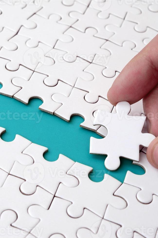 The human hand paves the way to the surface of the jigsaw puzzle, forming a blue space. The concept of overcoming the difficulties on the way to success photo