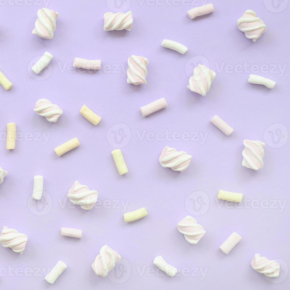 Colorful marshmallow laid out on violet paper background. pastel creative texture. minimal photo