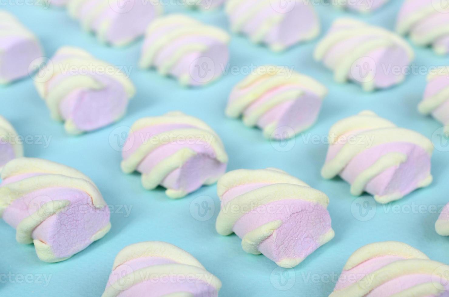 Colorful marshmallow laid out on blue paper background. pastel creative textured pattern. Perspective macro shot photo