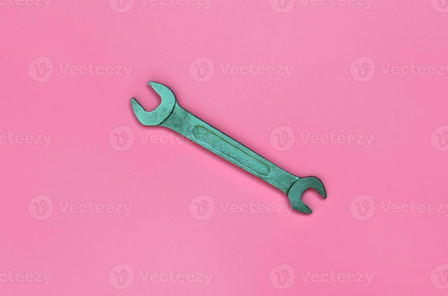 Metallic spanner lie on texture background of fashion pastel pink color paper in minimal concept photo