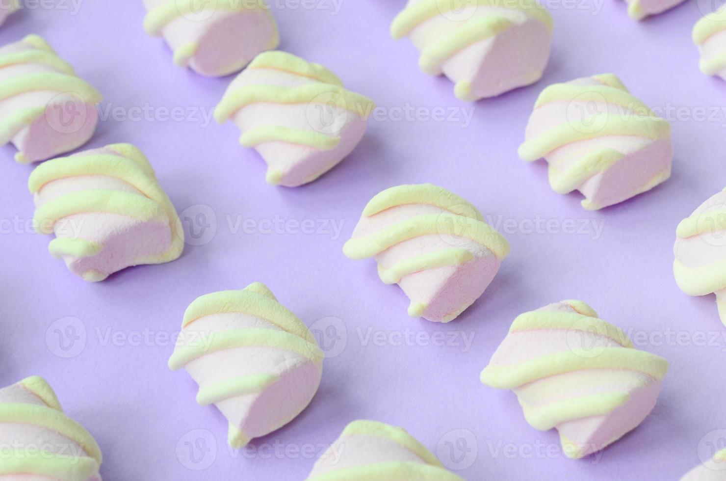 Colorful marshmallow laid out on violet paper background. pastel creative textured pattern. Perspective macro shot photo