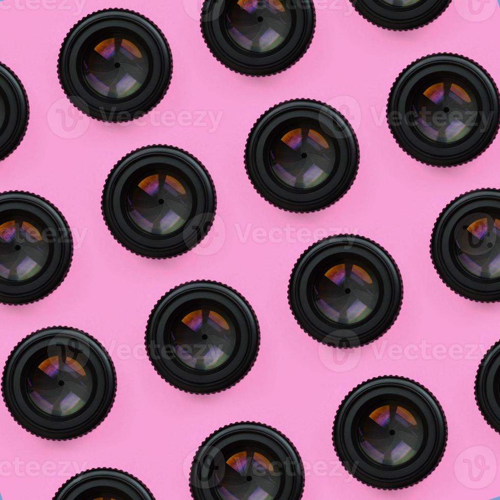 A few camera lenses with a closed aperture lie on texture background of fashion pastel pink color paper in minimal concept. Abstract trendy pattern photo