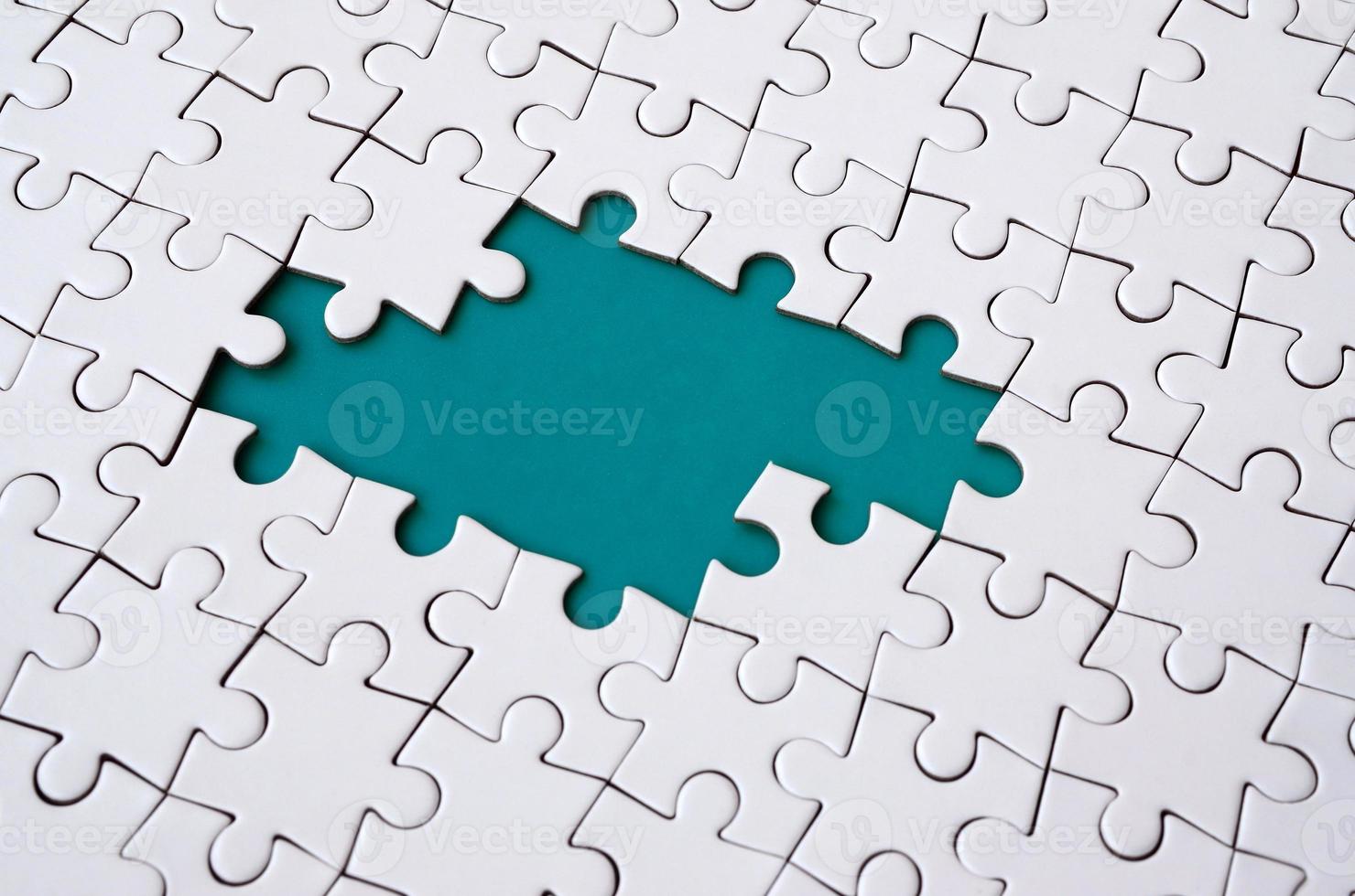 Close-up texture of a white jigsaw puzzle in assembled state with missing elements forming a blue pad for text. Copy space photo
