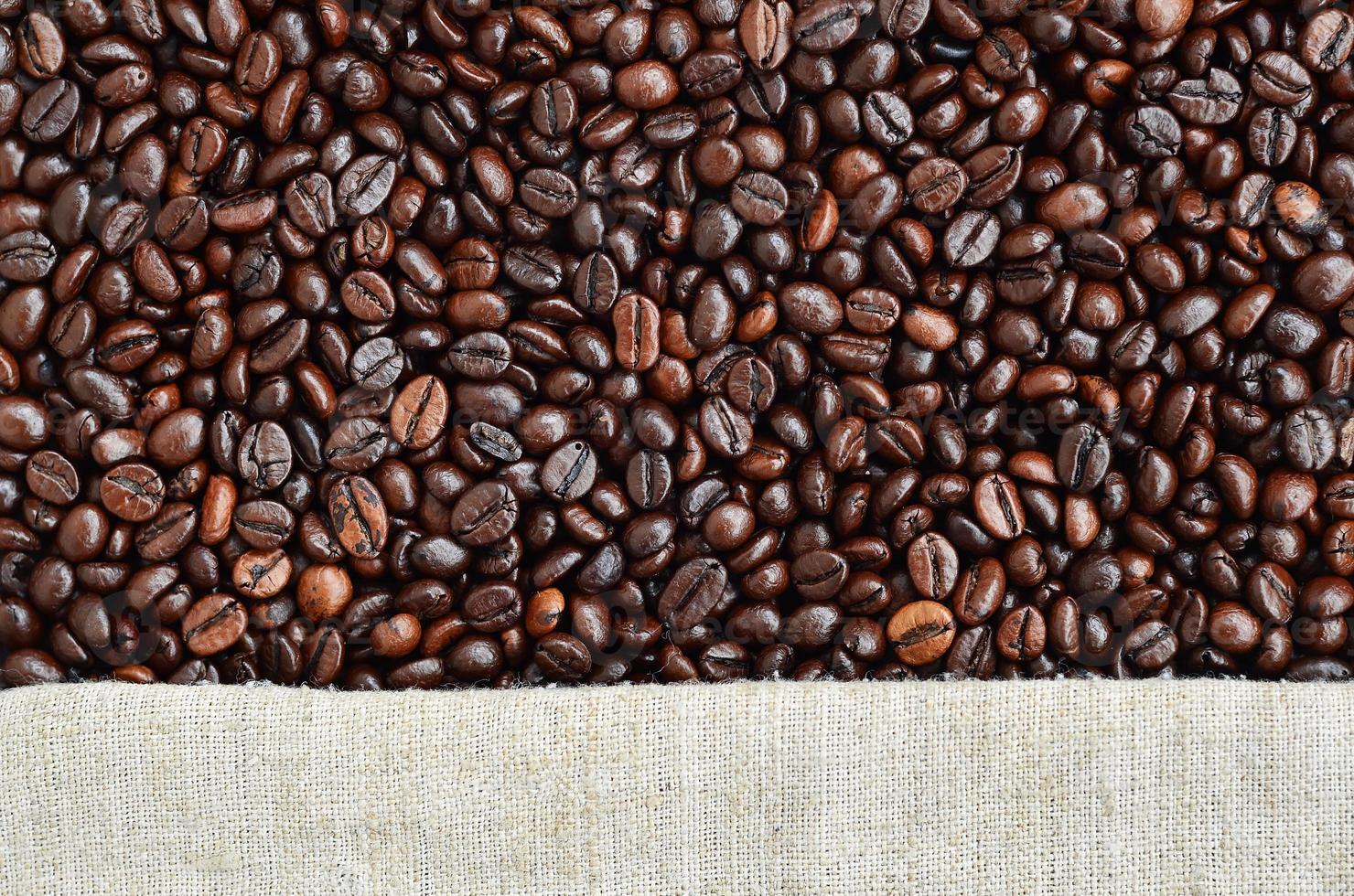 Texture of a gray canvas made of old and coarse burlap with coffee beans on it photo