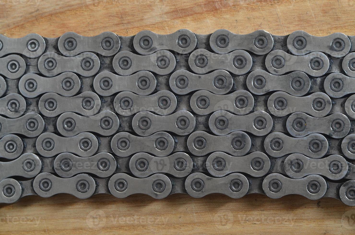 Dirty and oily chain from a mountain bike lying on a wooden table in a bicycle shop photo