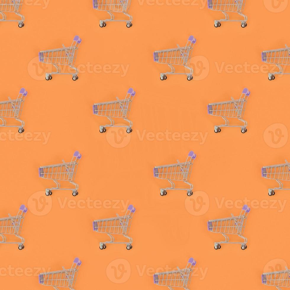 Shopping addiction, shopping lover or shopaholic concept. Many small empty shopping carts perform a pattern on a pastel colored paper background. Flat lay composition, top view photo