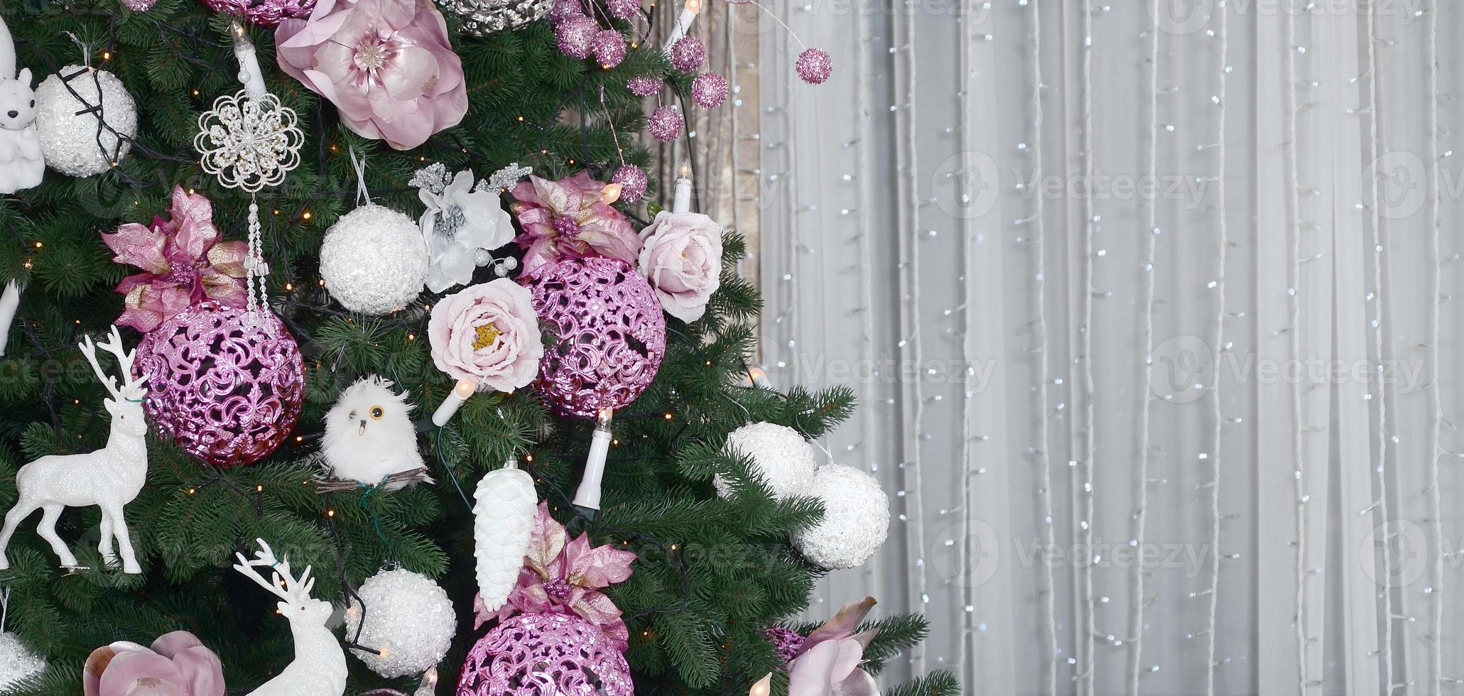 Decorating Christmas tree close up. Decoration bulb, fir tree, pink x-mas toys and lights. Use for Christmas and New years celebration background photo