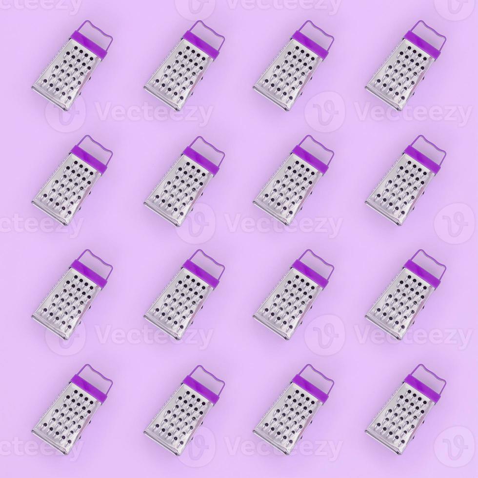Small stainless steel graters lies on a pastel colored paper. Kitchen accessories. Tools for cooking. Flat lay top view photo