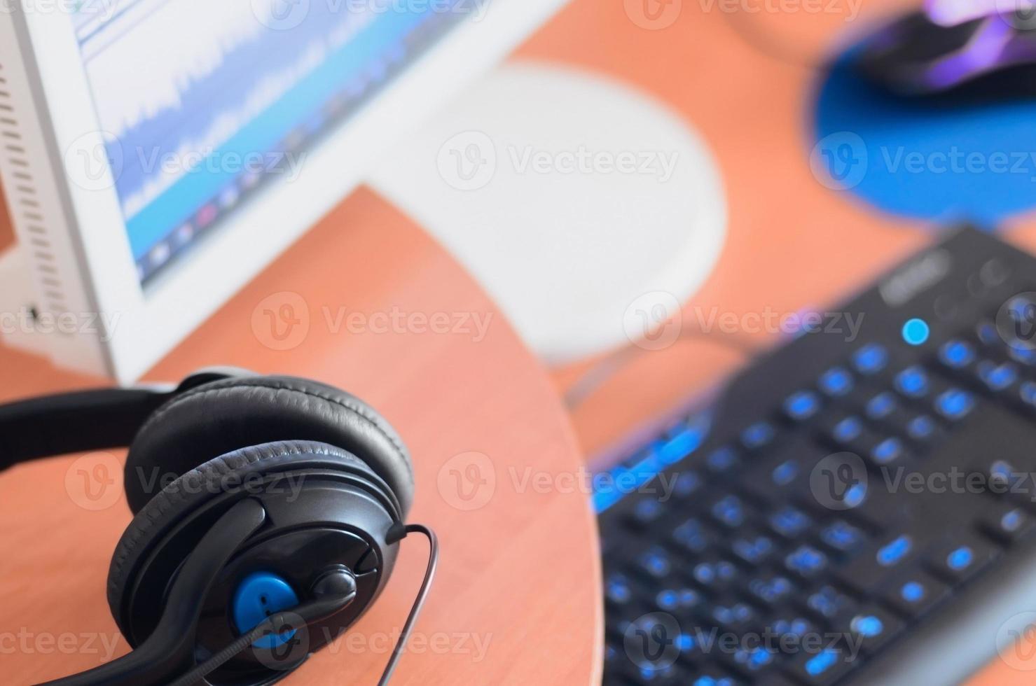 Big black headphones lie on the wooden desktop of the sound designer photo