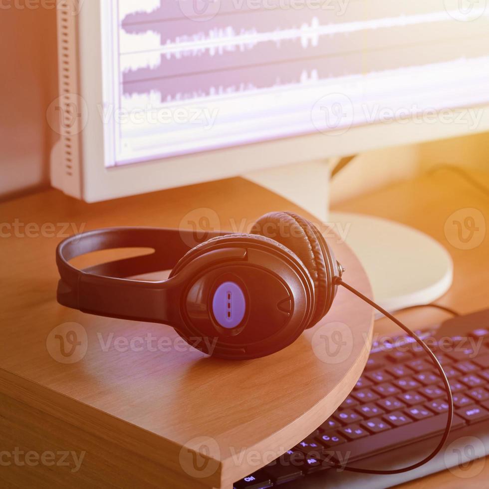 Big black headphones lie on the wooden desktop of the sound designer photo