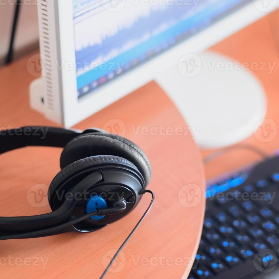 Big black headphones lie on the wooden desktop of the sound designer photo
